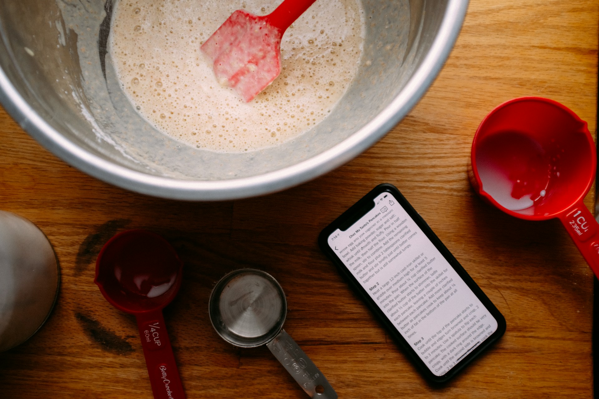 Mixing bowl on wood surface with recipe on phone nearby